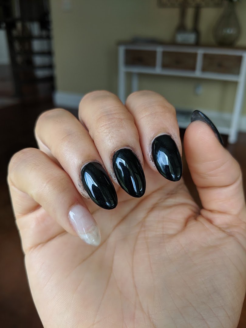 Manicured nails beside polish bottles.